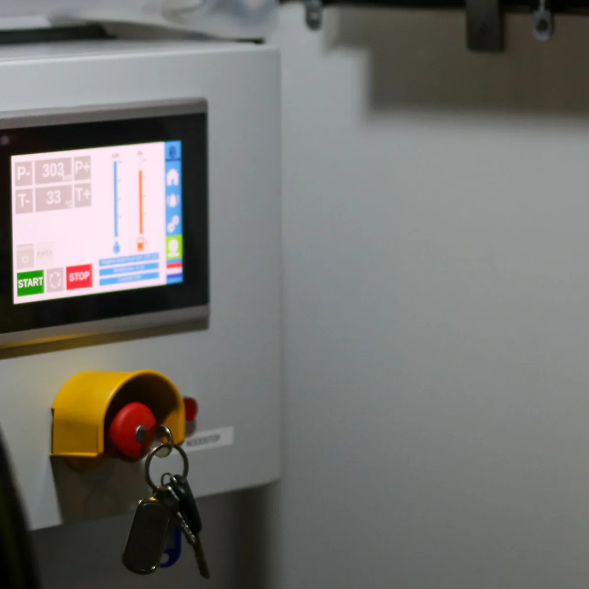 Control panel with a touchscreen display showing live readings, start and stop controls and an emergency stop button